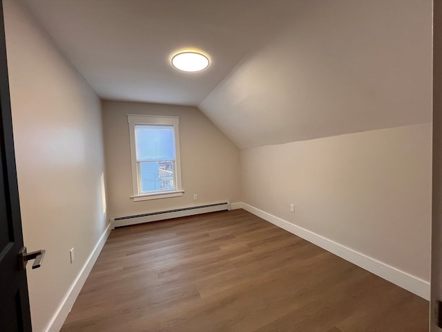 bonus room with a baseboard heating unit, hardwood / wood-style floors, and vaulted ceiling