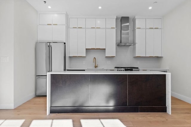 1 Marion St Unit 7, Cambridge, MA 02141 - kitchen with wall chimney range hood, high end fridge, white cabinets, a kitchen island with sink, and light countertops