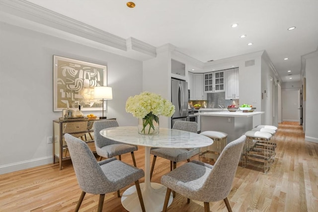 dining space featuring crown molding and light hardwood / wood-style flooring