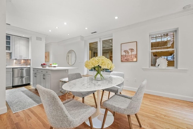 dining area with crown molding and light hardwood / wood-style flooring