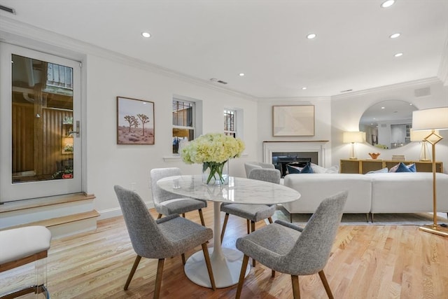 dining area with light wood-type flooring and ornamental molding