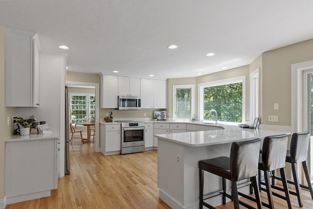 5 Mckinley Dr, Acton, MA 01720 - kitchen with stainless steel appliances, a peninsula, a sink, white cabinetry, and recessed lighting