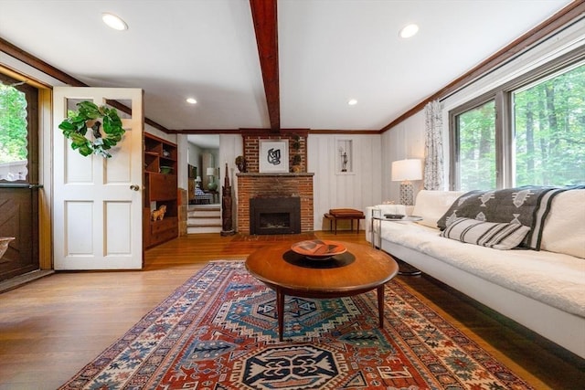 32 Fern St, Concord, MA 01742 - living room featuring healthy amount of natural light, wood finished floors, beamed ceiling, a brick fireplace, and crown molding