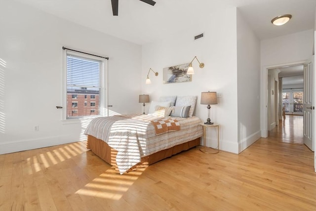 bedroom featuring baseboards, light wood-type flooring, and visible vents