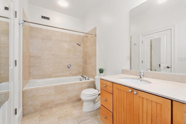 full bathroom featuring toilet, tiled shower / bath, vanity, and visible vents