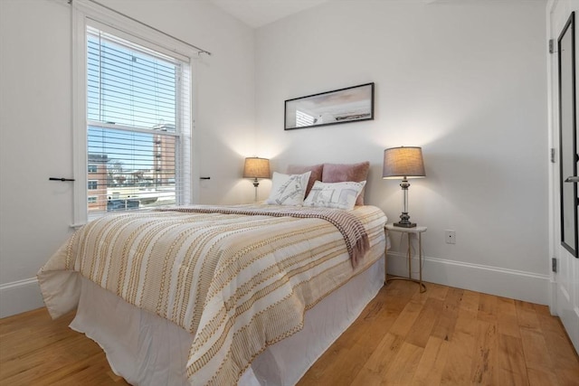bedroom featuring baseboards, multiple windows, and wood finished floors