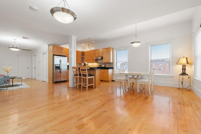 dining space featuring light wood finished floors, a notable chandelier, baseboards, and visible vents