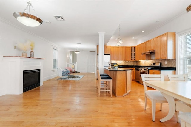 kitchen with under cabinet range hood, light wood-style flooring, stainless steel gas stove, and visible vents