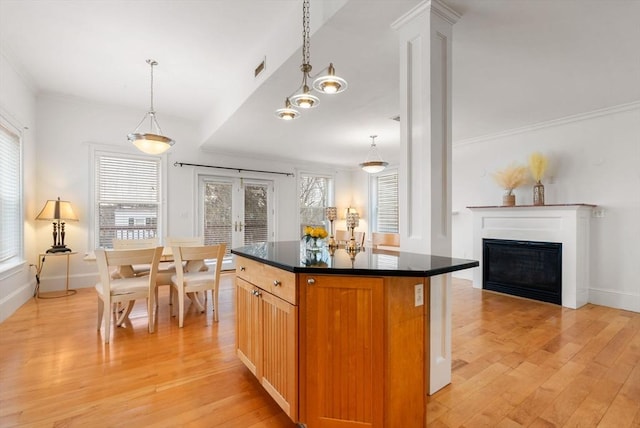 kitchen featuring dark countertops, a kitchen island, light wood-type flooring, and a glass covered fireplace
