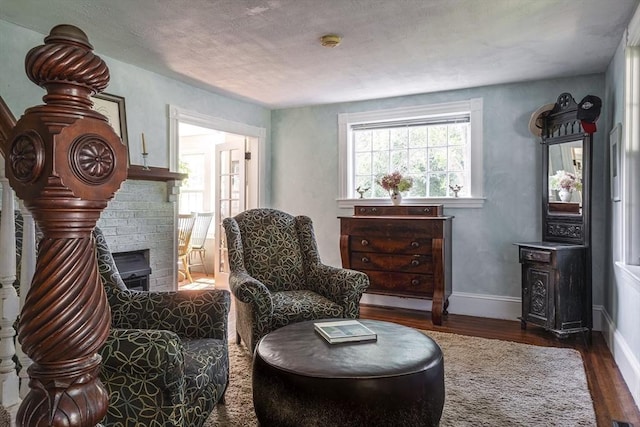 sitting room featuring baseboards, a brick fireplace, and wood finished floors