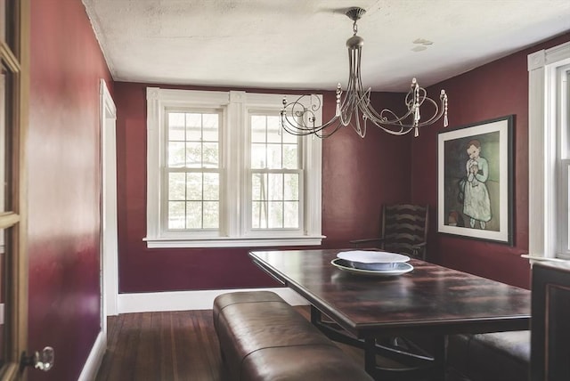 dining space with baseboards, a textured ceiling, wood finished floors, and a chandelier