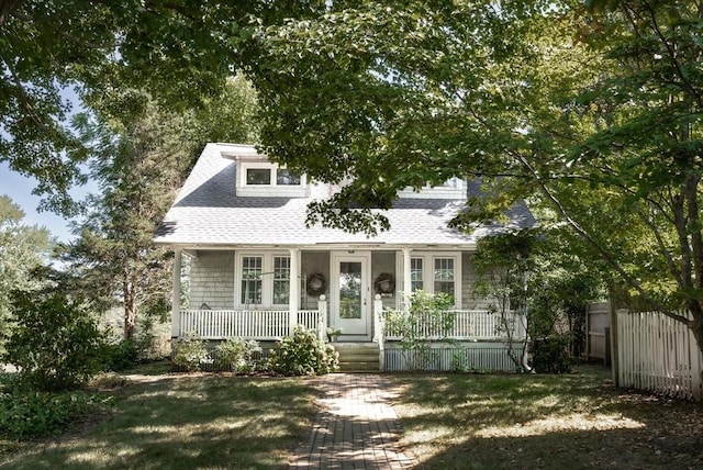 view of front of home featuring roof with shingles, fence, and covered porch
