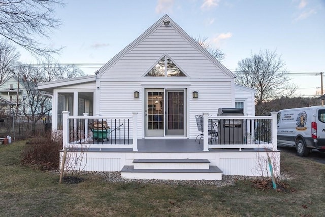 rear view of house with a lawn and a sunroom