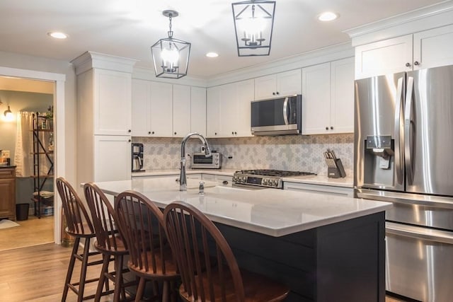 kitchen featuring a center island with sink, light wood-type flooring, appliances with stainless steel finishes, a kitchen bar, and white cabinetry