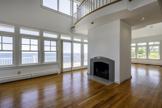 240 Atlantic Rd, Gloucester, MA 01930 - unfurnished living room featuring baseboard heating, a fireplace with flush hearth, wood finished floors, and a towering ceiling