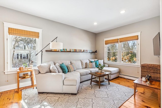 living room with a baseboard heating unit, recessed lighting, wood-type flooring, and plenty of natural light