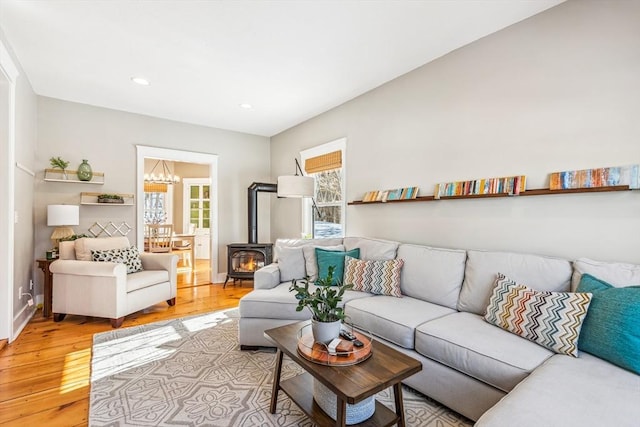 living area featuring recessed lighting, a wood stove, light wood-style flooring, and an inviting chandelier