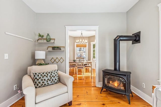 sitting room with light wood-type flooring, a wood stove, and baseboards