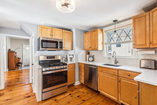 kitchen featuring light wood-style floors, appliances with stainless steel finishes, light countertops, and a sink