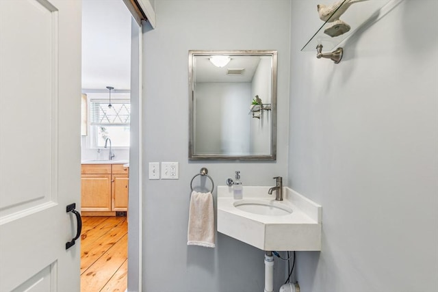 bathroom featuring visible vents, a sink, and wood finished floors