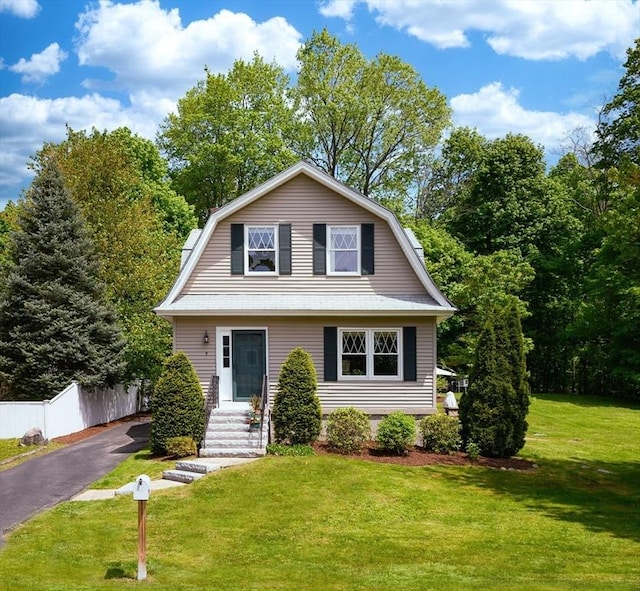 colonial inspired home featuring a front yard, fence, aphalt driveway, and a gambrel roof