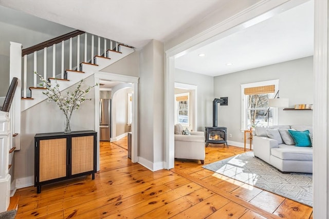 entryway with recessed lighting, baseboards, stairway, wood-type flooring, and a wood stove