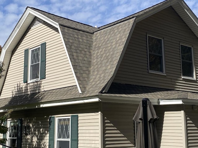 view of side of home featuring a shingled roof and a gambrel roof