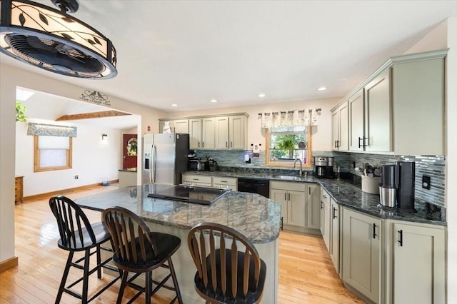 472 Potter Rd, Framingham, MA 01701 - kitchen featuring black appliances, light wood finished floors, decorative backsplash, a kitchen island, and a breakfast bar