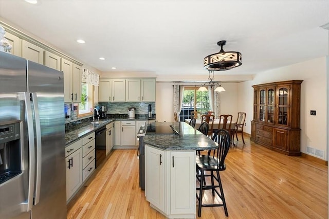 472 Potter Rd, Framingham, MA 01701 - kitchen with stainless steel fridge, black dishwasher, light wood-type flooring, a breakfast bar area, and backsplash