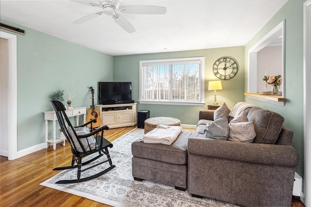 living room featuring baseboards, a ceiling fan, a barn door, and wood finished floors