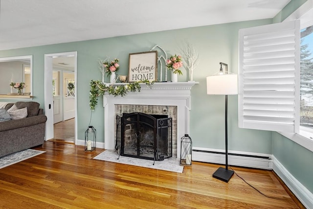 living room with baseboard heating, baseboards, a fireplace with flush hearth, and wood finished floors