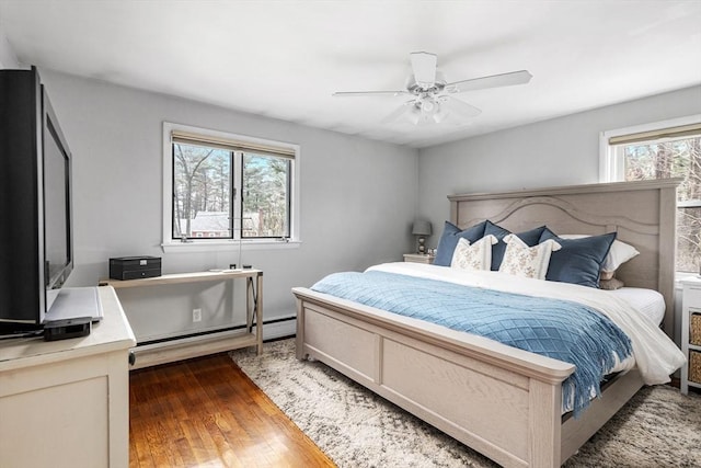 bedroom with a baseboard heating unit, hardwood / wood-style flooring, and ceiling fan