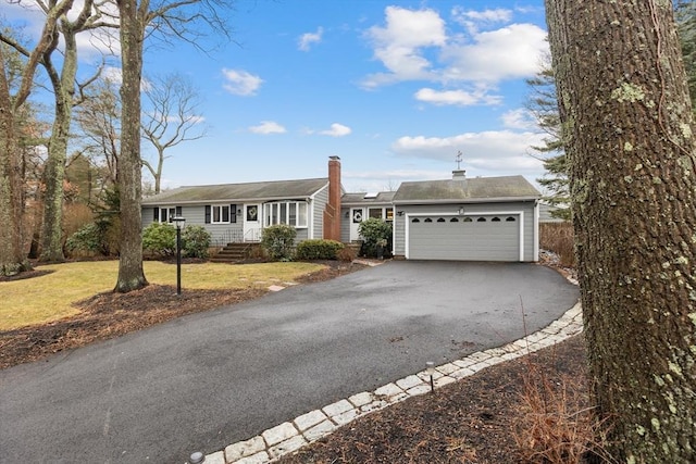 single story home with a front lawn, aphalt driveway, entry steps, a chimney, and a garage