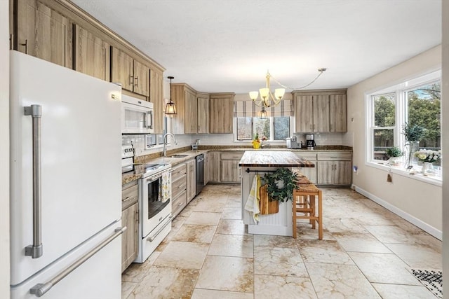 kitchen with a sink, tasteful backsplash, white appliances, an inviting chandelier, and baseboards