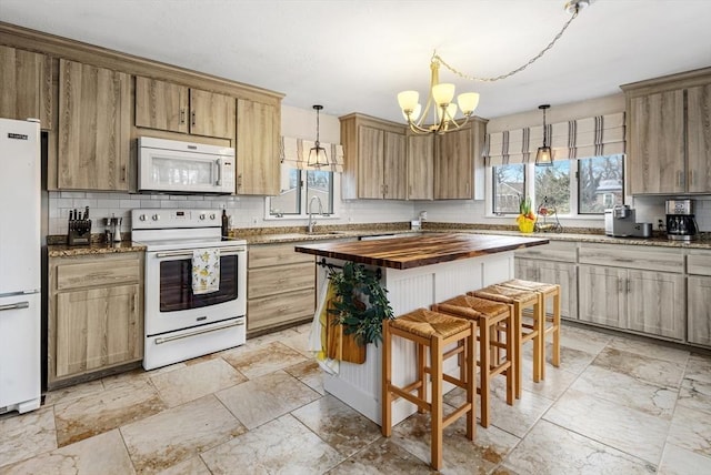 kitchen featuring white appliances, a healthy amount of sunlight, tasteful backsplash, and wood counters