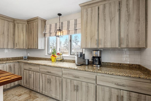 kitchen featuring light stone countertops, backsplash, pendant lighting, and light brown cabinets