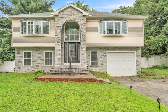 raised ranch featuring a garage and a front yard