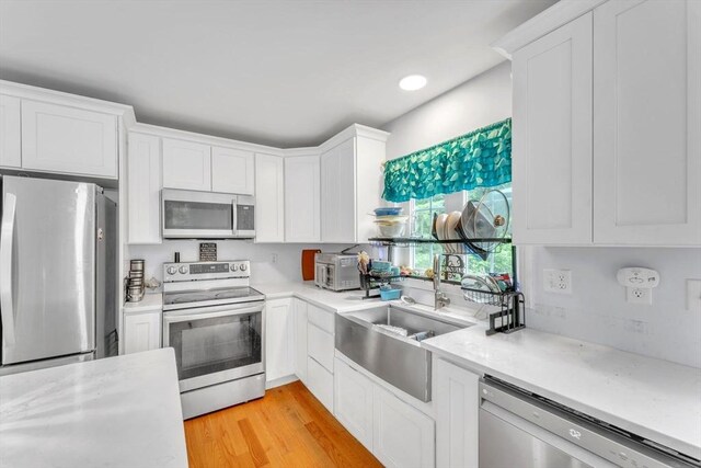 kitchen featuring sink, white cabinets, stainless steel appliances, and light hardwood / wood-style flooring