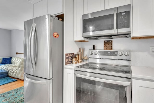 kitchen with appliances with stainless steel finishes, white cabinetry, and hardwood / wood-style flooring