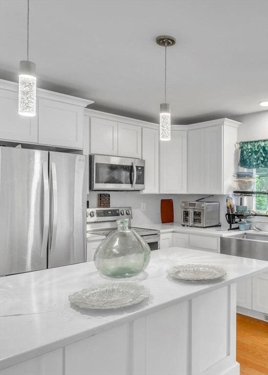 kitchen with white cabinets, stainless steel appliances, and decorative light fixtures