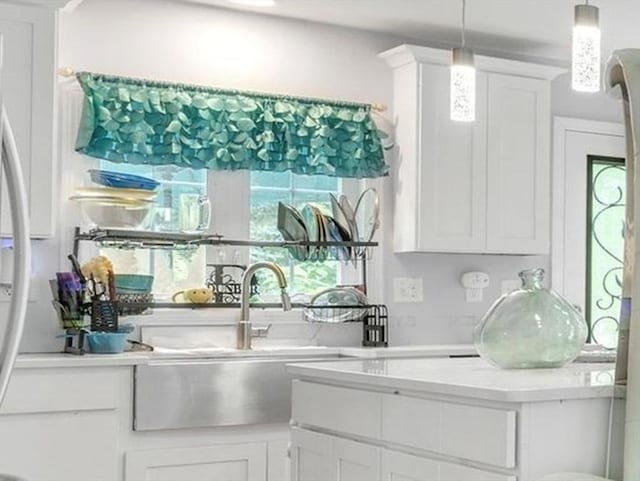 kitchen featuring white cabinets, hanging light fixtures, and sink