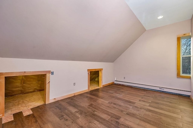 additional living space with vaulted ceiling, wood-type flooring, and a baseboard heating unit