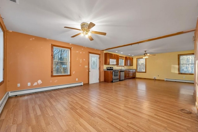 unfurnished living room with baseboard heating, a healthy amount of sunlight, and light wood-type flooring