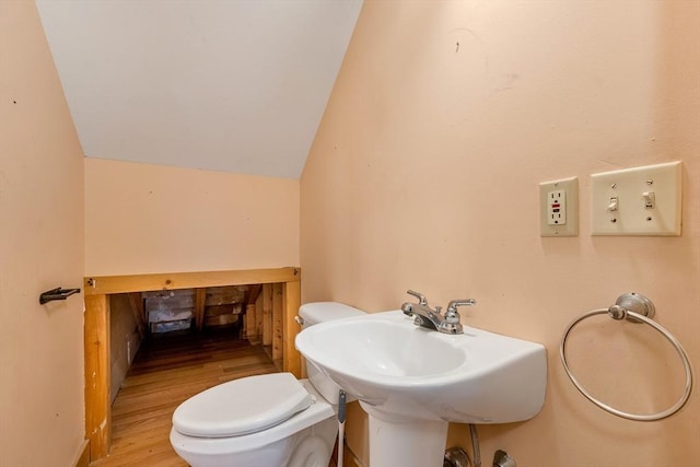 bathroom featuring toilet, wood-type flooring, sink, and vaulted ceiling