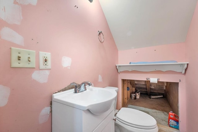 bathroom featuring vanity, toilet, and lofted ceiling