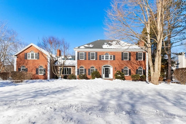 view of front of property featuring brick siding and a chimney