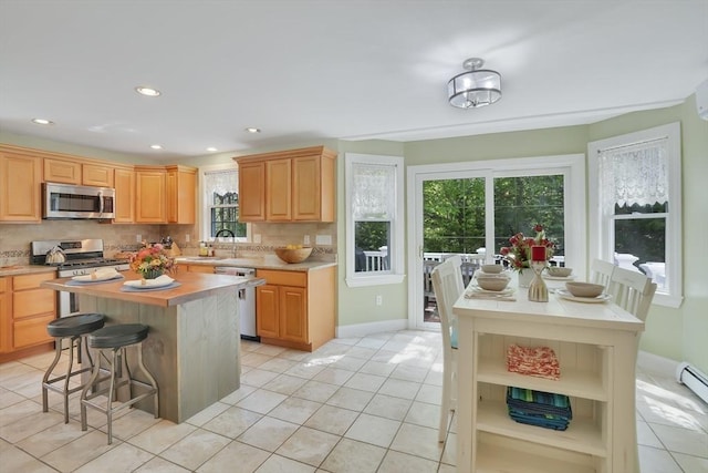 71 Sixth St N, Edgartown, MA 02539 - kitchen featuring appliances with stainless steel finishes, a sink, backsplash, light tile patterned flooring, and a kitchen island