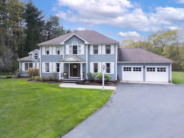 colonial-style house with a front lawn, aphalt driveway, and a garage