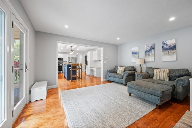 living area featuring light wood-type flooring, baseboards, and recessed lighting