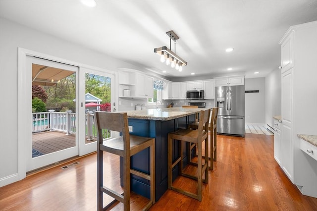 kitchen with white cabinetry, light stone counters, visible vents, and appliances with stainless steel finishes
